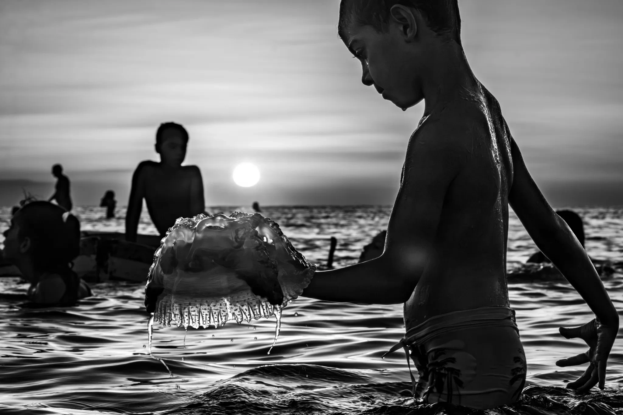 Baigneurs au coucher du soleil, un enfant au premier plan