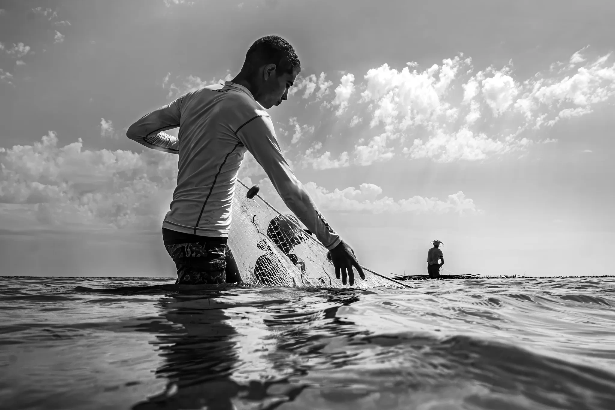Enfant debout dans l’eau, bateau à l’horizon